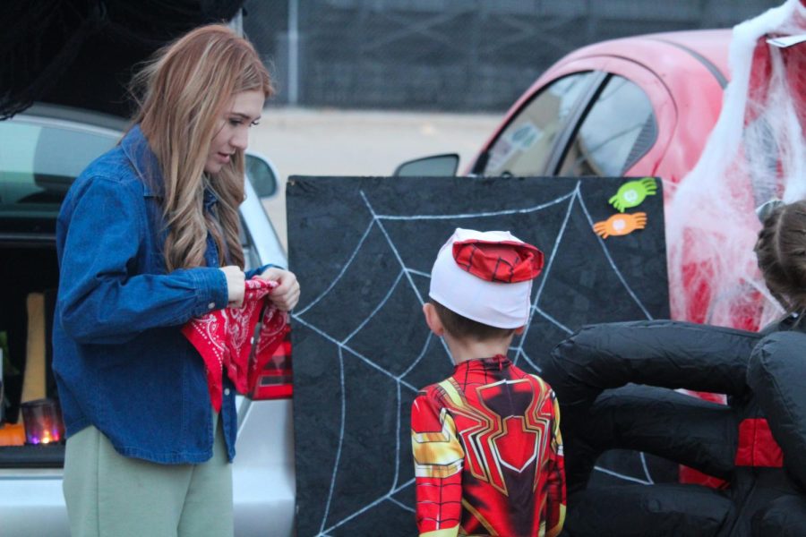 Junior Arianna Bonafilia explains her game to a young boy. Popular games at the event were cornhole, or games similar to it, though some had out of the box games such as stick the spider on the web.