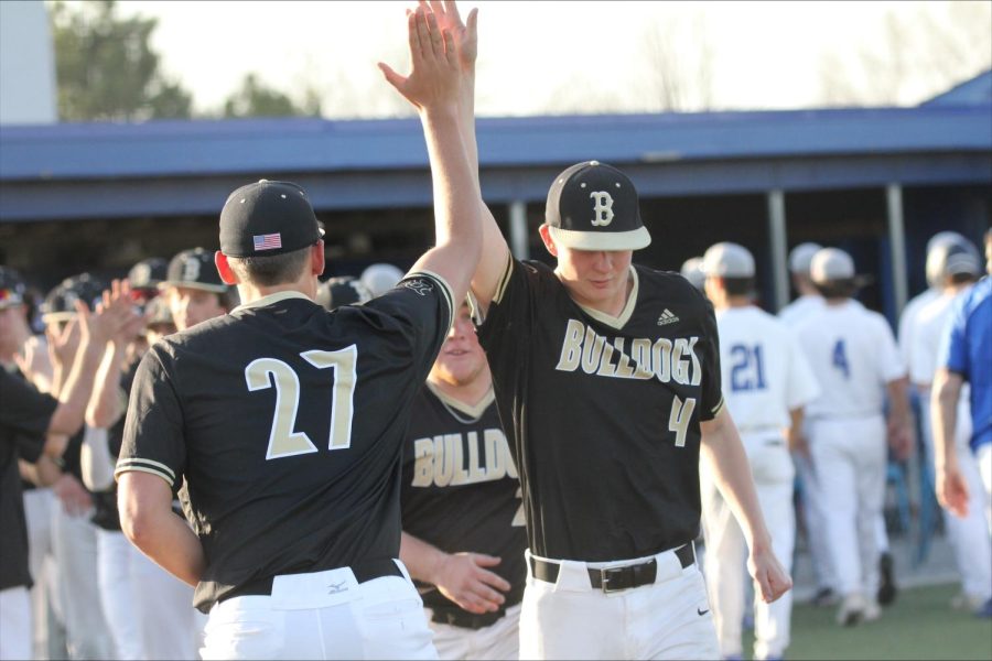 Seniors Ryne Renbarger, Holden Kleveter and Colin White celebrate their team win after defeating Millard North. The Bulldogs won the game with an ending score of 6-5.