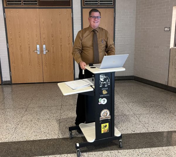 Principal Darren Rasmussen poses for a photo by the auditorium doors.