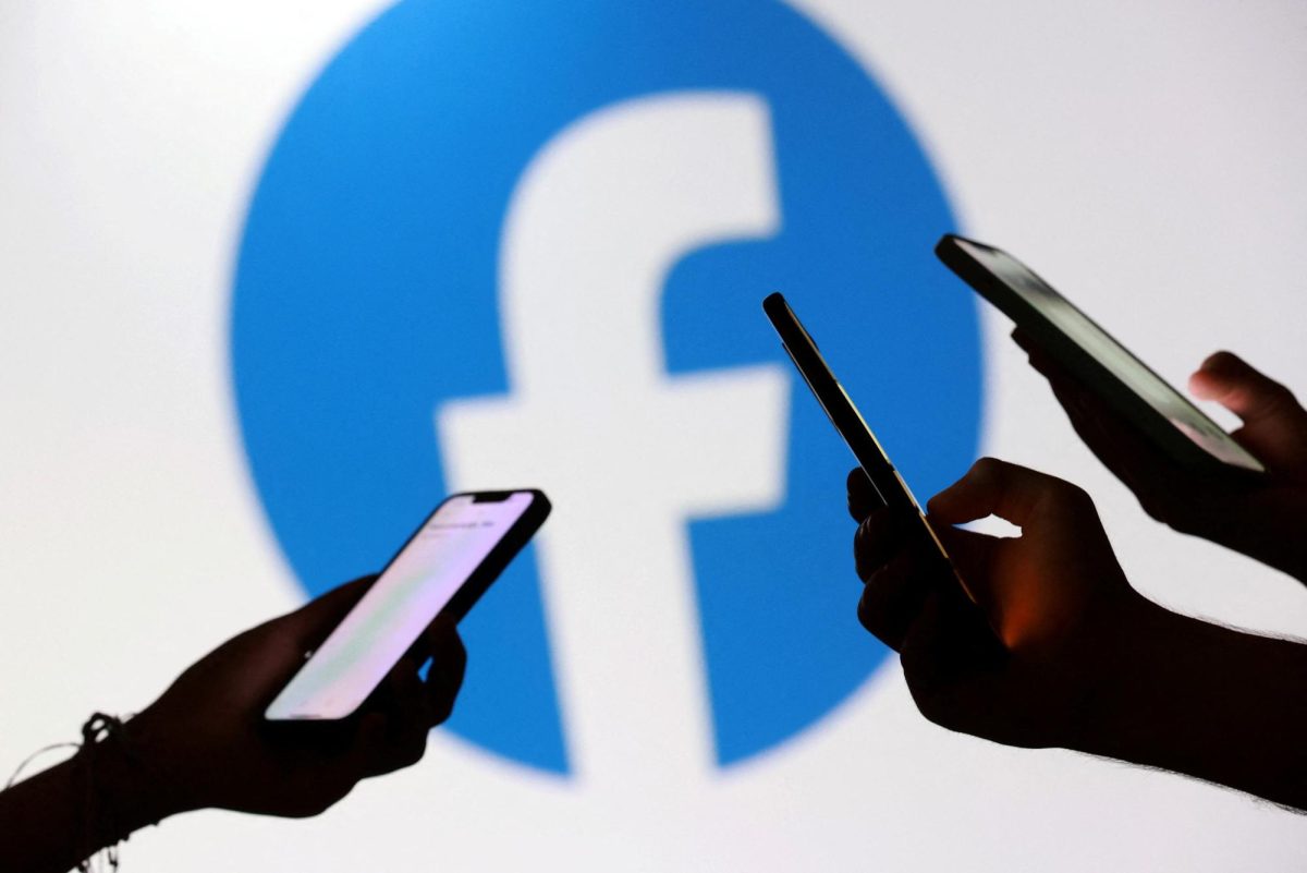 Teenagers pose for a photo while holding smartphones in front of a Facebook logo in this illustration taken September 11, 2025. REUTERS/Dado Ruvic/Illustration
