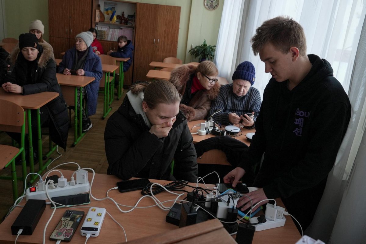 Residents wait while charging their devices inside a school classroom turned into a humanitarian aid point during a power blackout after critical civil infrastructure was hit by recent Russian missile and drone strikes, amid Russia's attack on Ukraine, in Kyiv, Ukraine January 11, 2026. REUTERS/Anna Voitenko