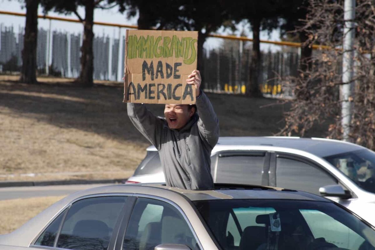 Protester standing in the sun-roof of their car during ICE walkout protest.
